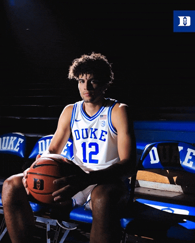 A Duke Basketball Player Sits On A Bench Holding A Ball GIF