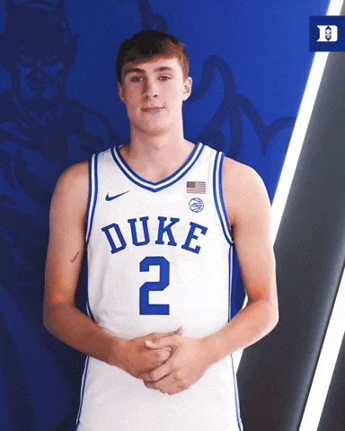A Duke Basketball Player Stands With His Hands Folded In Front Of A Blue Background GIF