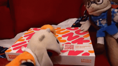 A Dunkin Donuts Box Sits On A Couch Next To Stuffed Animals GIF