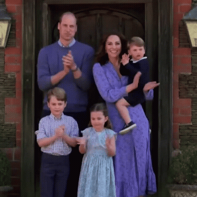 A Family Is Posing For A Picture In Front Of A Door While Clapping . GIF