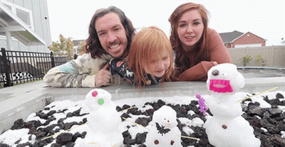 A Family Is Posing For A Picture In Front Of A Pile Of Snowmen GIF
