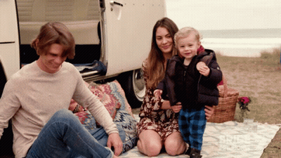 A Family Is Sitting On A Blanket In Front Of A Van GIF