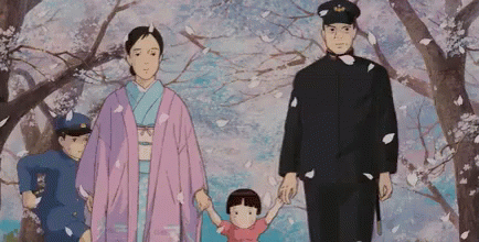 A Family Is Walking Through A Park With Cherry Blossoms Falling From The Trees . GIF