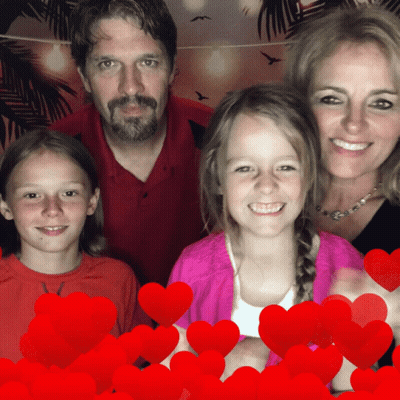 A Family Posing For A Picture With Red Hearts Behind Them GIF