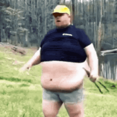 A Fat Man In A Blue Shirt And Shorts Is Standing In The Grass . GIF