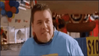 A Fat Man In A Blue Shirt Is Standing In Front Of A $ 10 Sign . GIF