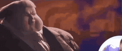 A Fat Man In A Suit And Tie Is Sitting Next To A Globe . GIF