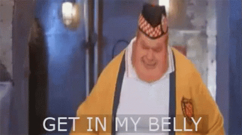 A Fat Man Wearing A Yellow Sweater And A Hat Is Standing In A Room And Saying `` Get In My Belly '' . GIF