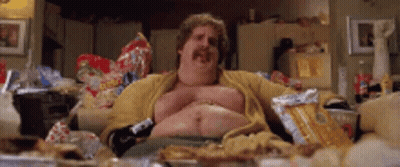 A Fat Man With A Mustache Is Sitting On A Couch Eating Chips . GIF