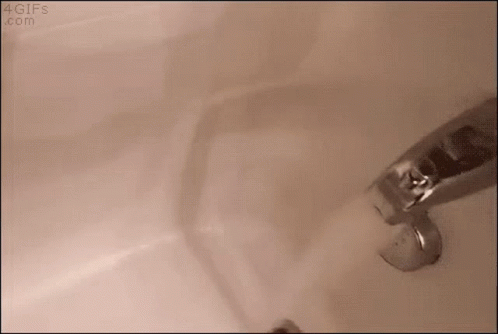 A Faucet Is Turned On In A Bathroom Sink And Water Is Coming Out Of It . GIF