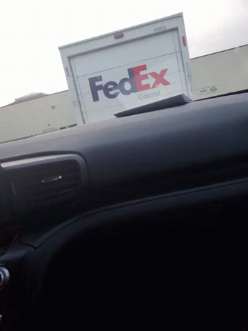 A Fedex Truck Is Parked On The Side Of A Building GIF