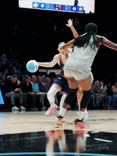 A Female Basketball Player Dribbles The Ball While Another Player Tries To Block Her GIF