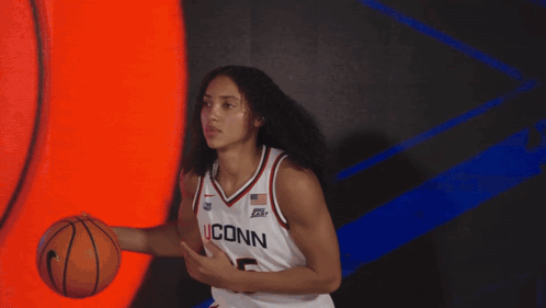 A Female Basketball Player For The Iconn Team Is Holding A Basketball GIF