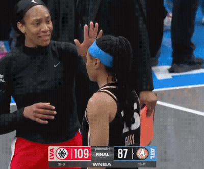 A Female Basketball Player High Fives Another Female Basketball Player During A Game GIF