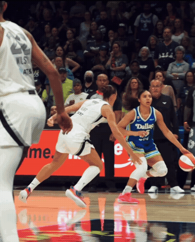 a female basketball player wearing a dallas jersey is dribbling the ball