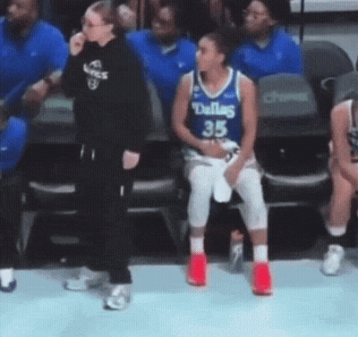 A Female Basketball Player Wearing A Dallas Jersey Is Sitting In The Stands . GIF