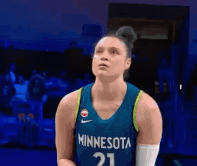a female basketball player wearing a minnesota jersey is looking up at the sky .