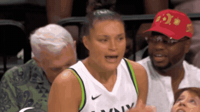 a female basketball player wearing a nike jersey is talking to a man in a red hat