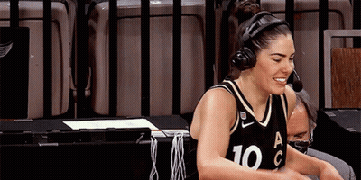 A Female Basketball Player Wearing Headphones And A Number 10 Jersey Is Sitting At A Table . GIF