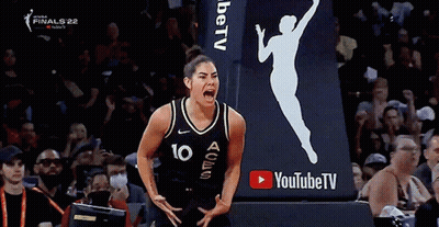 A Female Basketball Player With The Number 10 On Her Jersey Is Screaming In Front Of A Youtube Tv Sign . GIF