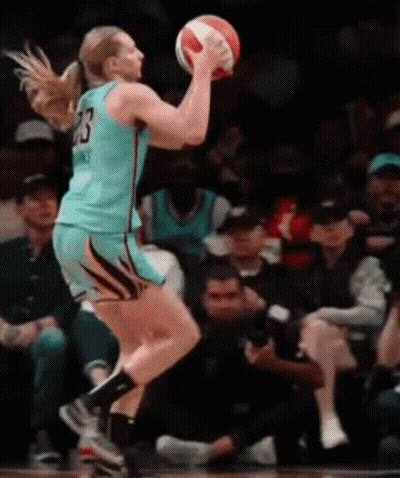 A Female Basketball Player With The Number 23 On Her Jersey Is Jumping To Catch The Ball GIF