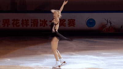A Female Figure Skater Is Performing In Front Of A Sign That Says World Championship GIF