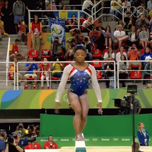 A Female Gymnast Is Doing A Trick On A Balance Beam In Front Of A Crowd At The Rio2016 Olympics GIF