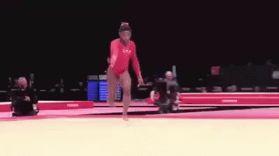A Female Gymnast Is Doing A Trick On A Mat . GIF