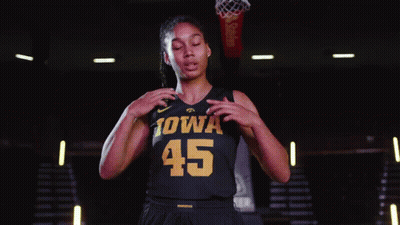 A Female Iowa Basketball Player Stands In Front Of A Basketball Net GIF