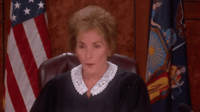 A Female Judge Is Sitting In A Courtroom With Her Eyes Closed And A Flag In The Background . GIF