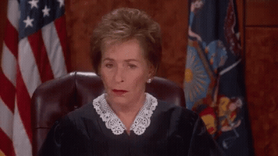 A Female Judge Is Sitting In Front Of An American Flag And Making A Funny Face . GIF