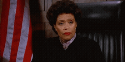 A Female Judge Is Sitting In Front Of An American Flag In A Courtroom . GIF
