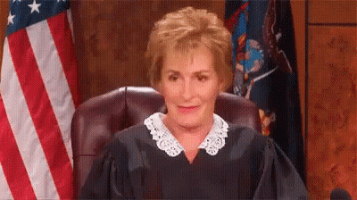 A Female Judge Is Sitting In Front Of An American Flag In A Courtroom . GIF