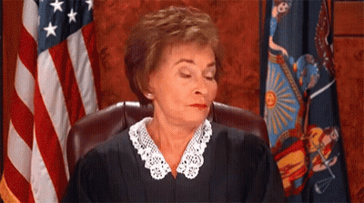 A Female Judge Is Sitting In Front Of An American Flag In A Courtroom . GIF