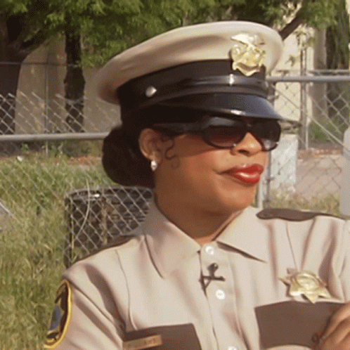 A Female Police Officer Wearing Sunglasses And A Hat With A Badge That Says Sheriff GIF