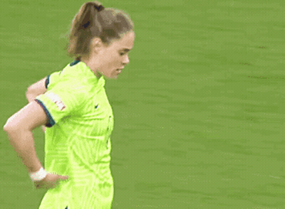 A Female Soccer Player In A Neon Green Jersey Is Standing On The Field . GIF