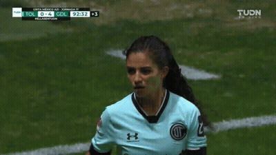 A Female Soccer Player Wearing A Blue Under Armour Jersey Stands On A Field GIF