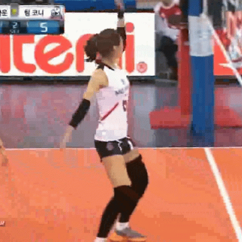 A Female Volleyball Player Is Jumping In The Air On A Court . GIF