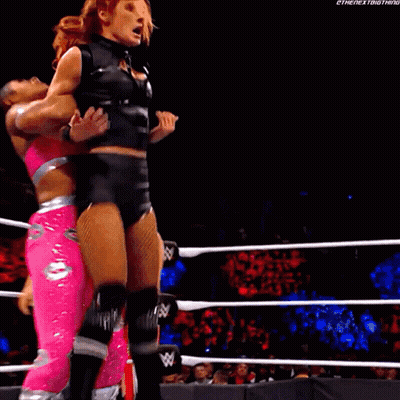 A Female Wrestler Is Being Lifted By Another Wrestler In A Wrestling Ring GIF