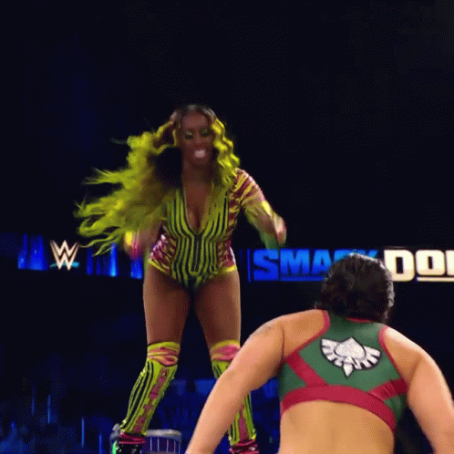 A Female Wrestler Is Being Lifted In The Air By Another Wrestler In A Ring GIF