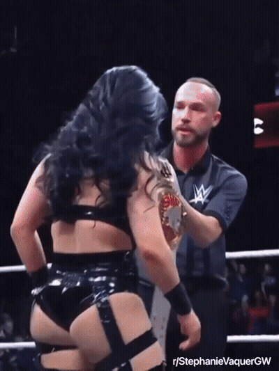 A Female Wrestler Is Holding A Wrestling Championship Belt While Standing Next To A Referee GIF