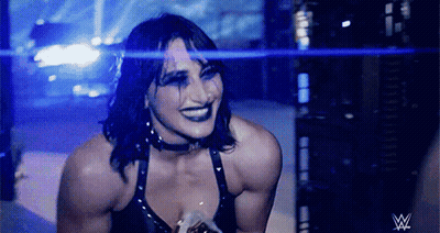 A Female Wrestler Is Smiling In Front Of A W Logo GIF