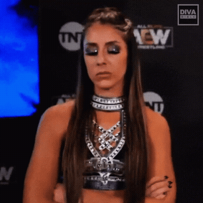 A Female Wrestler Is Standing With Her Arms Crossed In Front Of A Tnt Sign . GIF