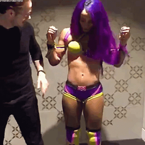 A Female Wrestler With Purple Hair Is Standing Next To A Man . GIF