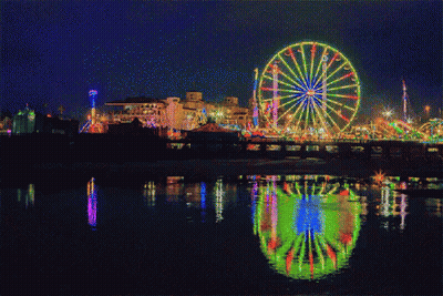 A Ferris Wheel Is Lit Up At A Carnival At Night GIF
