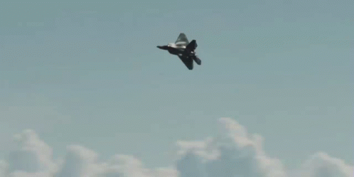 A Fighter Jet Flies Through A Cloudy Sky GIF