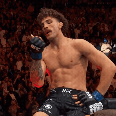 A Fighter Wearing Shorts That Say Ufc Is Standing In Front Of A Crowd GIF