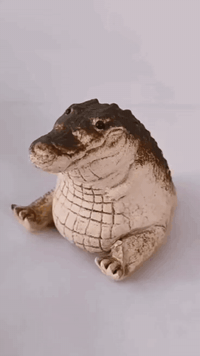 A Figurine Of An Alligator Wearing A Gold Crown GIF