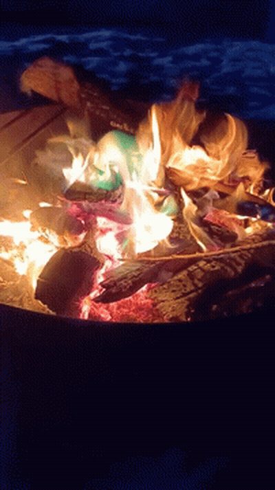 A Fire Is Being Lit With A Can Of Coca Cola In It GIF