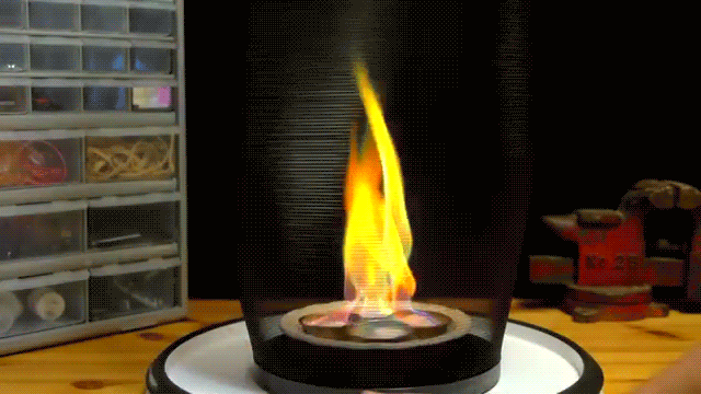 A Fire Is Burning In A Glass Container On A Table In Front Of A Toolbox That Says ' Bosch ' On It GIF